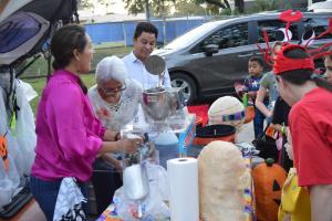 Photo of parents volunteering and interacting with children at a Trunk or Treat Halloween Event